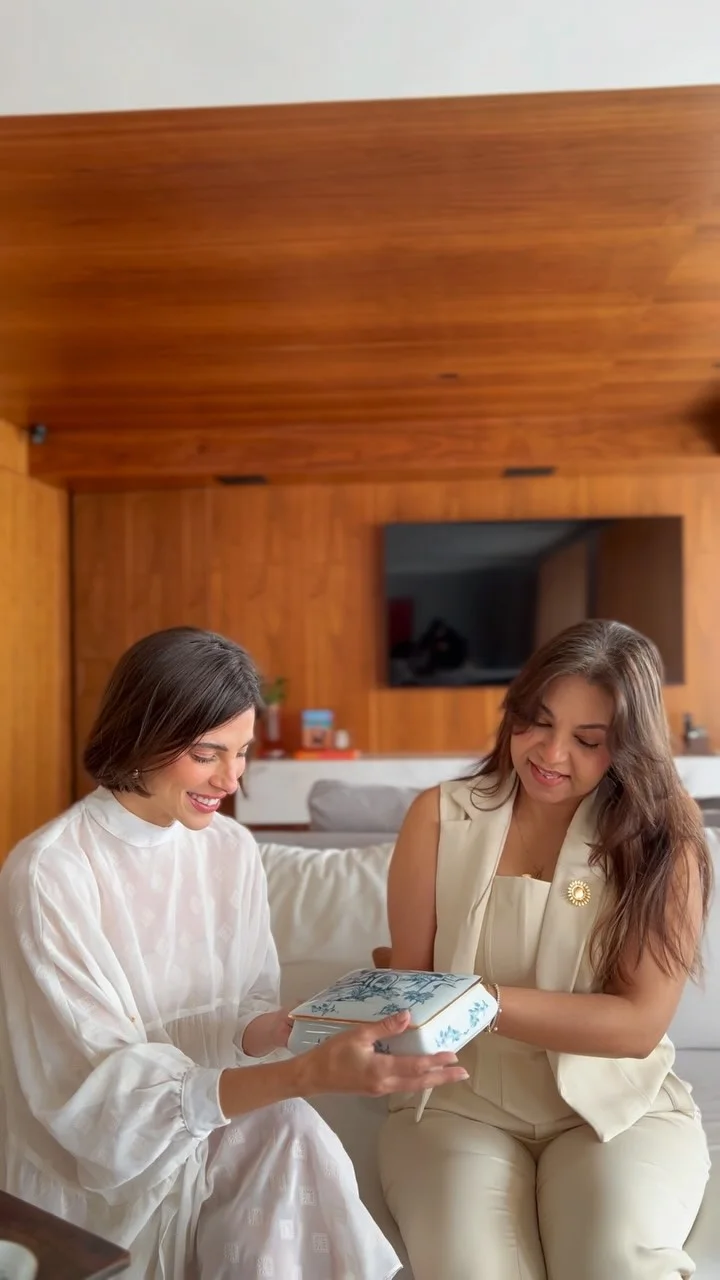 Katia entregando uma peça de porcelana azul a uma cliente no ateliê
