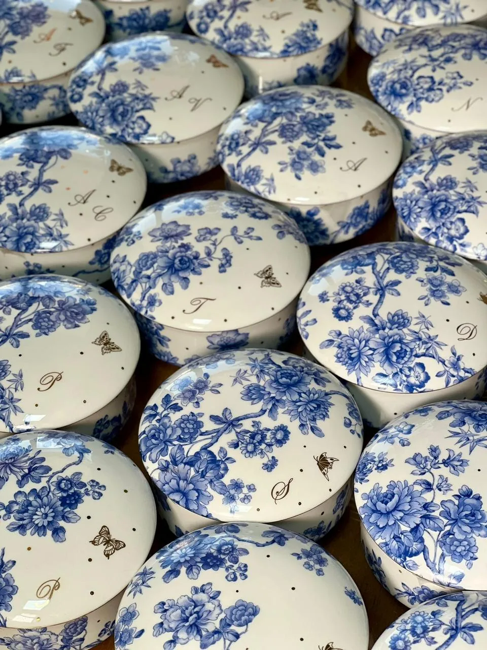 Conjunto de caixas redondas com florais azuis, borboletas e iniciais em ouro