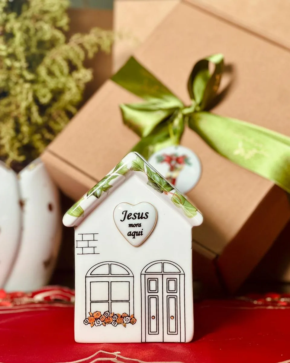 Casinha de porcelana com telhado de folhas e coração com a frase Jesus mora aqui, laço verde