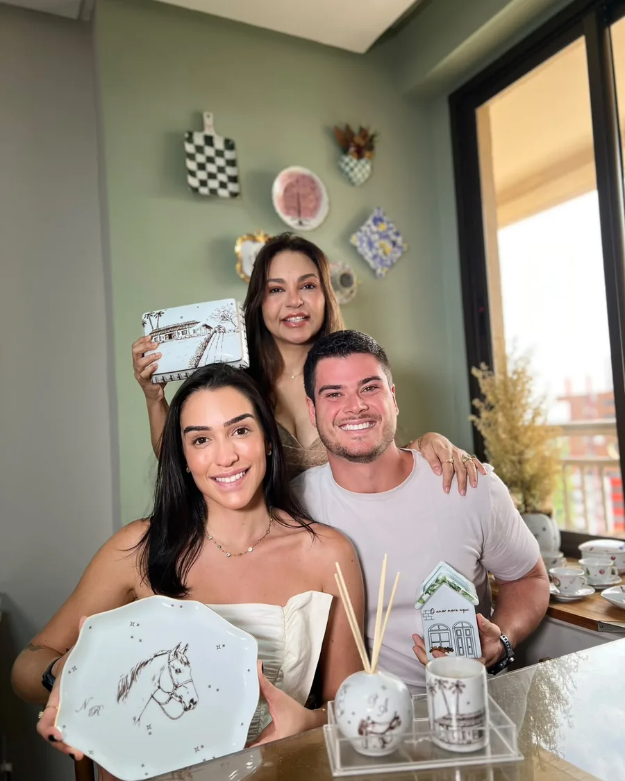 Nat e Rafa com a Katia no ateliê, segurando o prato com cavalo, o difusor e a casinha do kit