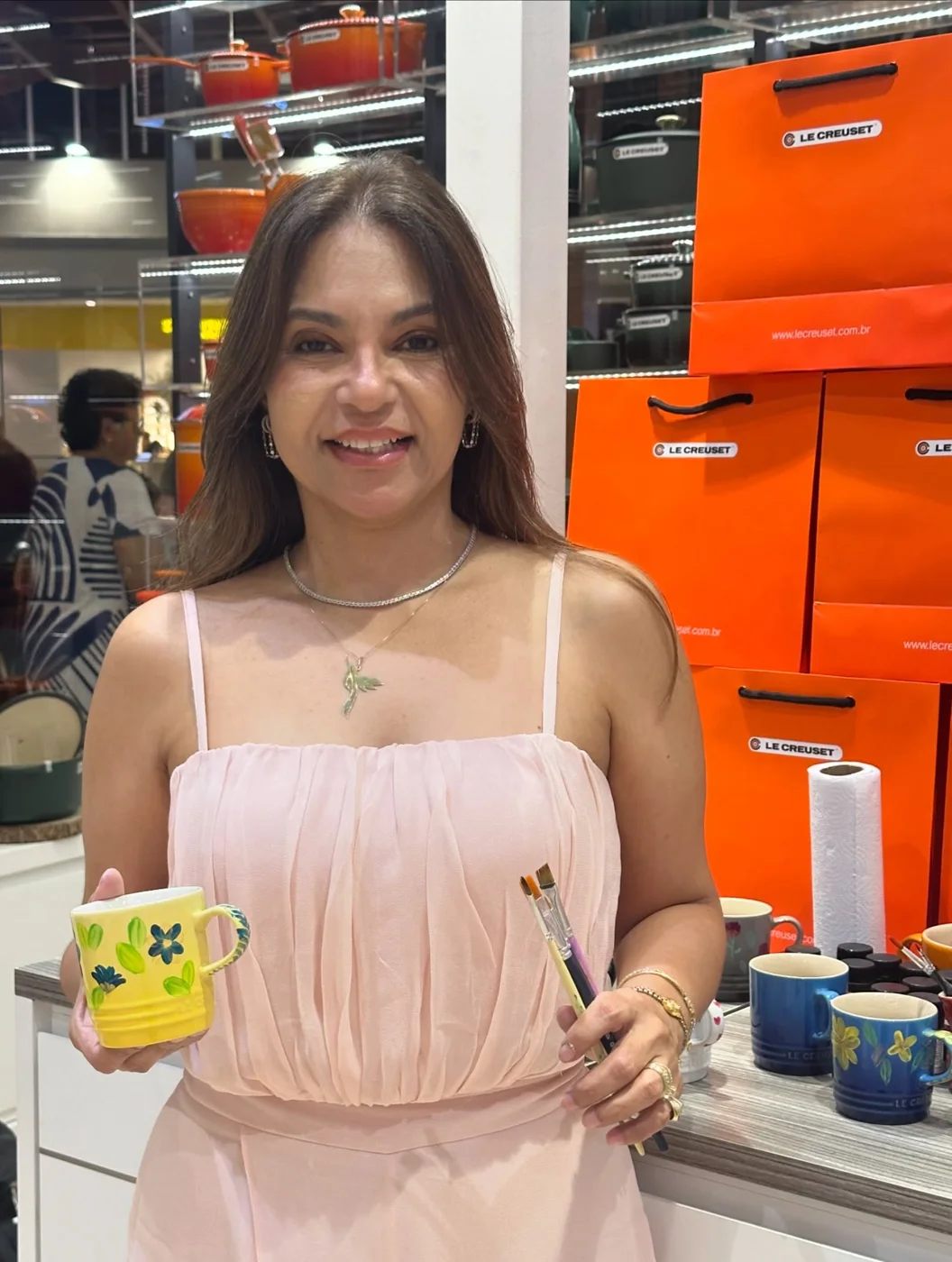 Katia Torquato sorrindo enquanto segura uma caneca de porcelana pintada à mão